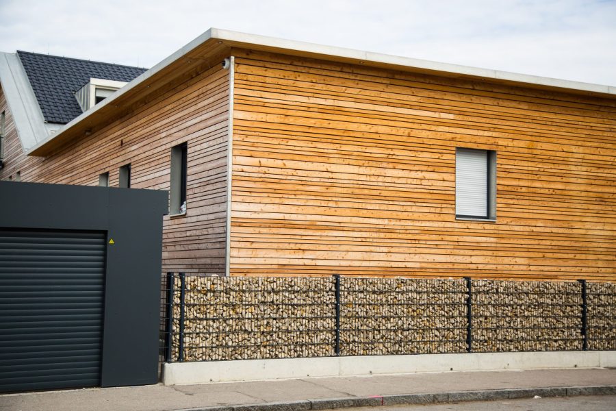 Modern wooden house with stone fence in front