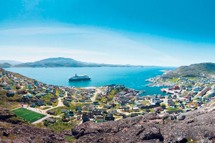 Panoramic shot of the coast at Greenland, Qaqortoq with a boat sailing in the sea